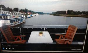 un tavolo e sedie su un balcone con barca di Hausboot Levitate im Hafen von Barßel a Barßel