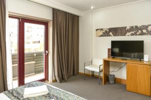 una camera d'albergo con TV e finestra di Dom Joao Hotel a Entroncamento