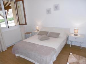 una camera da letto con un grande letto bianco con due cuscini di Le Lou Secadou a Saint-André-dʼAllas