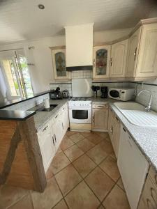 una cucina con armadietti bianchi ed elettrodomestici bianchi di Le Lou Secadou a Saint-André-dʼAllas