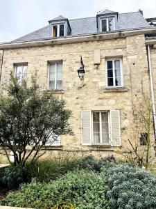 an old stone house with white windows and bushes at La vue sacrée in Laon