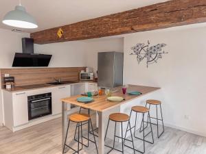 a kitchen with a wooden table and stools at Entre Bressuire & Thouars- By R&G in Coulonges-Thouarsais