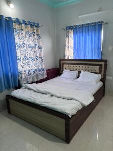 Bett in einem Zimmer mit blauen Vorhängen in der Unterkunft Forest villa 2bhk danawali in Panchgani