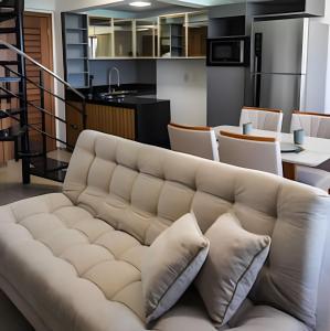 ein Wohnzimmer mit Sofa und eine Küche in der Unterkunft Cobertura duplex de frente pro mar in Natal