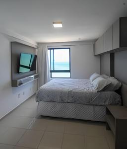 ein Schlafzimmer mit einem Bett und einem Fernseher darin in der Unterkunft Cobertura duplex de frente pro mar in Natal