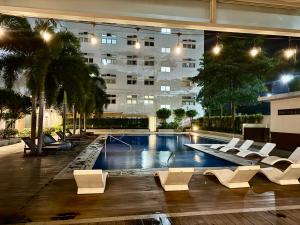 ein Pool mit weißen Stühlen und ein Gebäude in der Unterkunft J&A Cozy Calm Stay in Biñan + 13 Fotos