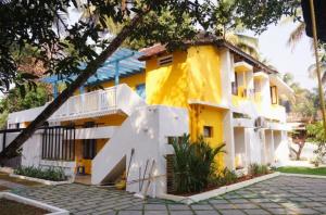 ein gelbes Haus mit einem Baum davor in der Unterkunft The Boho Stays Kochi in Kochi