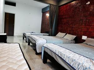 - une rangée de lits dans une chambre dotée d'un mur en briques dans l'établissement greenSpun nature Stay, à Somvārpet
