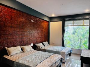 deux lits dans une chambre avec un mur de briques dans l'établissement greenSpun nature Stay, à Somvārpet