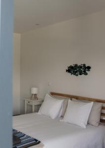 a bed with white pillows and a clock on the wall at Canhoto Douro in Marco de Canaveses +61 photos