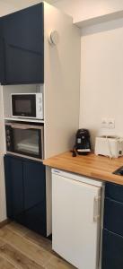 een keuken met blauwe kasten en een aanrecht met een magnetron bij Le Nénuphar in Vernon