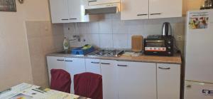 une cuisine avec des armoires blanches et un comptoir dans l'établissement Apartman Villy 2, à Jadranovo 32 autres photos