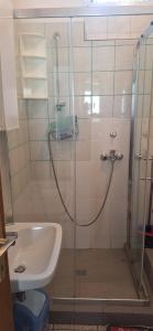 une douche avec une porte vitrée à côté d'un lavabo dans l'établissement Apartman Villy 2, à Jadranovo
