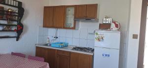 une cuisine avec un réfrigérateur blanc et des placards en bois dans l'établissement Apartman Villy 2, à Jadranovo