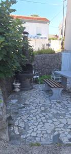 une terrasse en pierre avec un banc et une table dans l'établissement Apartman Villy 2, à Jadranovo