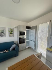Una sala de estar con un sofá azul y una cocina. en Smeraldo Apartment, en Palau
