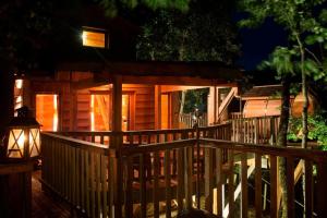 eine Holzhütte mit einer Veranda in der Nacht in der Unterkunft Bois Des Nauzes in Seyches + 8 Fotos