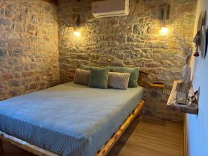 Bett in einem Zimmer mit einer Steinmauer in der Unterkunft Suite of Villa Lagkadaki in Agriliá