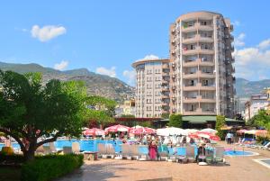 um resort com piscina e um edifício ao fundo em Club Sidar Apart Hotel em Alanya
