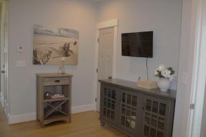 a living room with a television and a dresser with a table at 410A The Jetty House in Virginia Beach