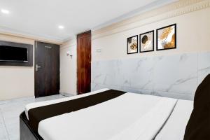 een slaapkamer met een wit bed en een tv bij Hotel O AK International Hotel in Calcutta