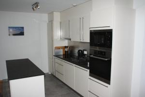 a kitchen with white cabinets and black appliances at Chesery 8 in Morgins