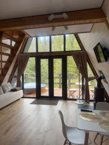 salon z dużymi oknami oraz stołem i krzesłami w obiekcie Лісовий Трикутник w mieście Mikuliczyn