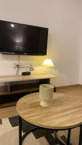 a living room with a table and a tv on a wall at Flat in Viman Nagar in Pune +5 photos