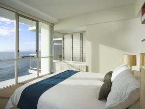 a bedroom with a large bed and a large window at Grand Mercure Apartments Magnetic Island in Nelly Bay