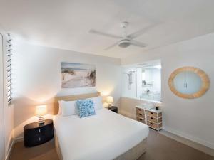 a bedroom with a white bed and a mirror at Grand Mercure Apartments Magnetic Island in Nelly Bay