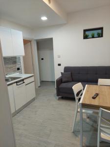 Una cocina y una sala de estar con un sofá y una mesa. en Appartamento a MXP Aeroporto-Via Mameli, en Somma Lombardo