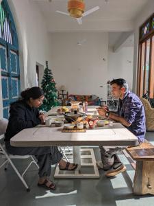 Um homem e uma mulher sentados à mesa comendo. em Boutique Homestay With Art Center in Courtyard House em Udaipur