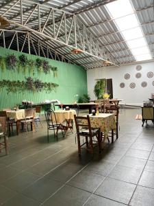a restaurant with tables and chairs and a green wall at Villa da Serra Pousada in Piumhi