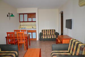 a living room with a table and chairs and a kitchen at Club Sidar Apart Hotel in Alanya