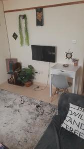 a living room with a tv and a desk with a chair at Swali residence in Nakuru