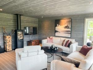 a living room with white couches and a tv at Modern Cabin By Hardangervidda in Garden