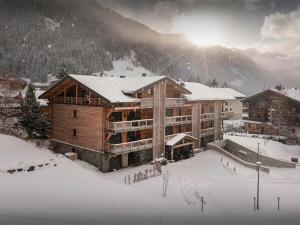 a large building in the snow with the sun behind it at Lodge Cresson - OVO Network in Châtel