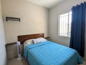a bedroom with a bed with a blue comforter and a window at Via Trip House - Sonsonate in Sonsonate