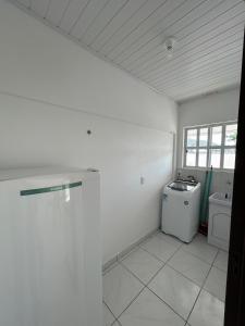 Habitación blanca con lavadora y ventana en Apartamento Orquídea, en Porto Belo 4 fotos más