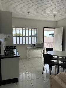 cocina con fogones y mesa con sillas en Apartamento Orquídea, en Porto Belo