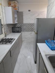 uma cozinha branca com um frigorífico e um lavatório em عمارات ميلسا سيتى ستارز em Banī Ghālib