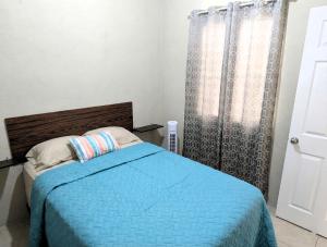 a bedroom with a bed with a blue blanket at Via Trip House - Sonsonate in Sonsonate