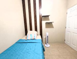 a small bedroom with a bed with a blue blanket at Via Trip House - Sonsonate in Sonsonate