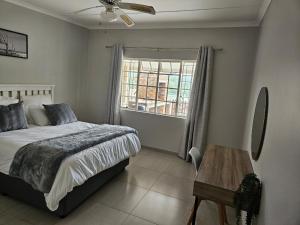 Un dormitorio con una cama y una mesa y una ventana. en 48 Cintsa Bay, en Cintsa West