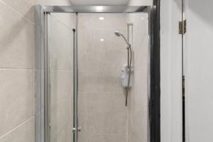 a shower with a glass door in a bathroom at Stylish Studio and Parking Fast access Central London in Perivale