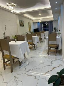 a restaurant with white tables and chairs and marble floors at Maxi Palace hotel in Capitão Leônidas Marques