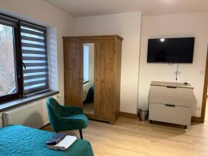 a bedroom with a bed and a chair and a television at Wynajmowanie pokoi in Szczyglice