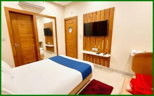 Un dormitorio con una cama y un televisor de pantalla plana. en Mahakaleshwar Jyotirlinga Temple Hotel A- Palace Near Railway Station - Parking with Room Service, fully air Conditioning Rooms - Best Hotel in Ujjain, en Ujjain
