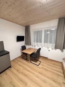 een kamer met een houten tafel en stoelen en een televisie bij Alpin Studio Schladming 101 in Schladming