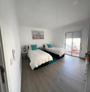 een witte kamer met 2 bedden en een raam bij DyLary in Armação de Pêra